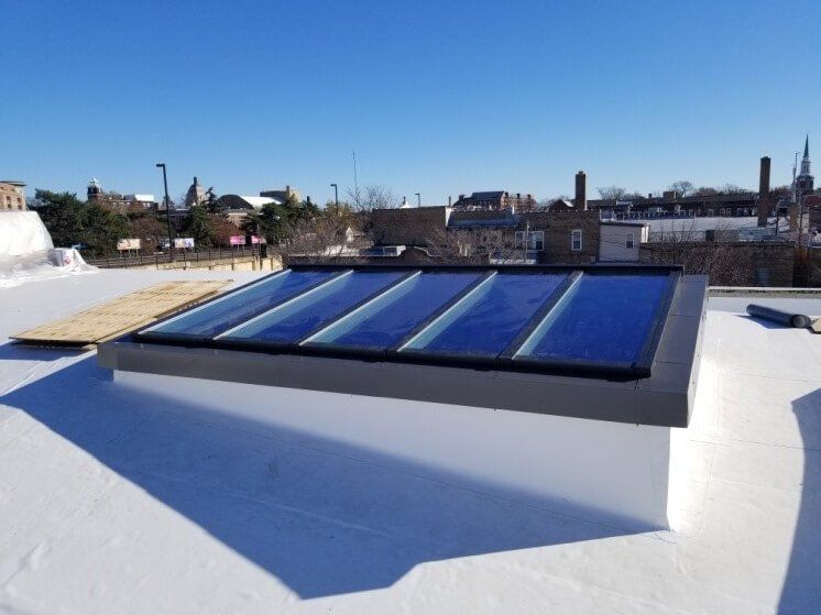 A skylight on top of a white roof with a blue sky in the background