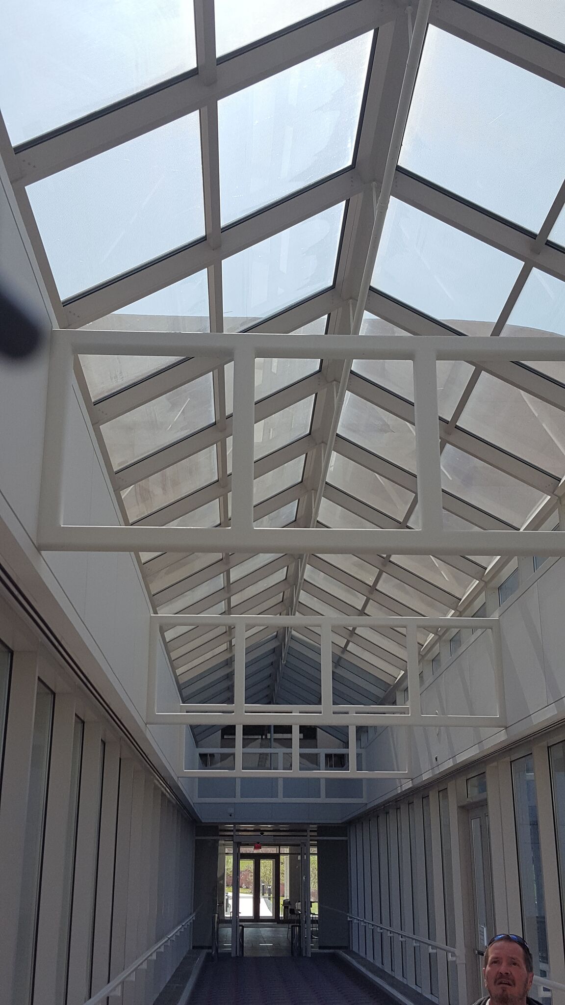 A man is standing in a hallway with a glass ceiling.