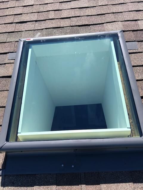A skylight on top of a roof with a clear glass window.
