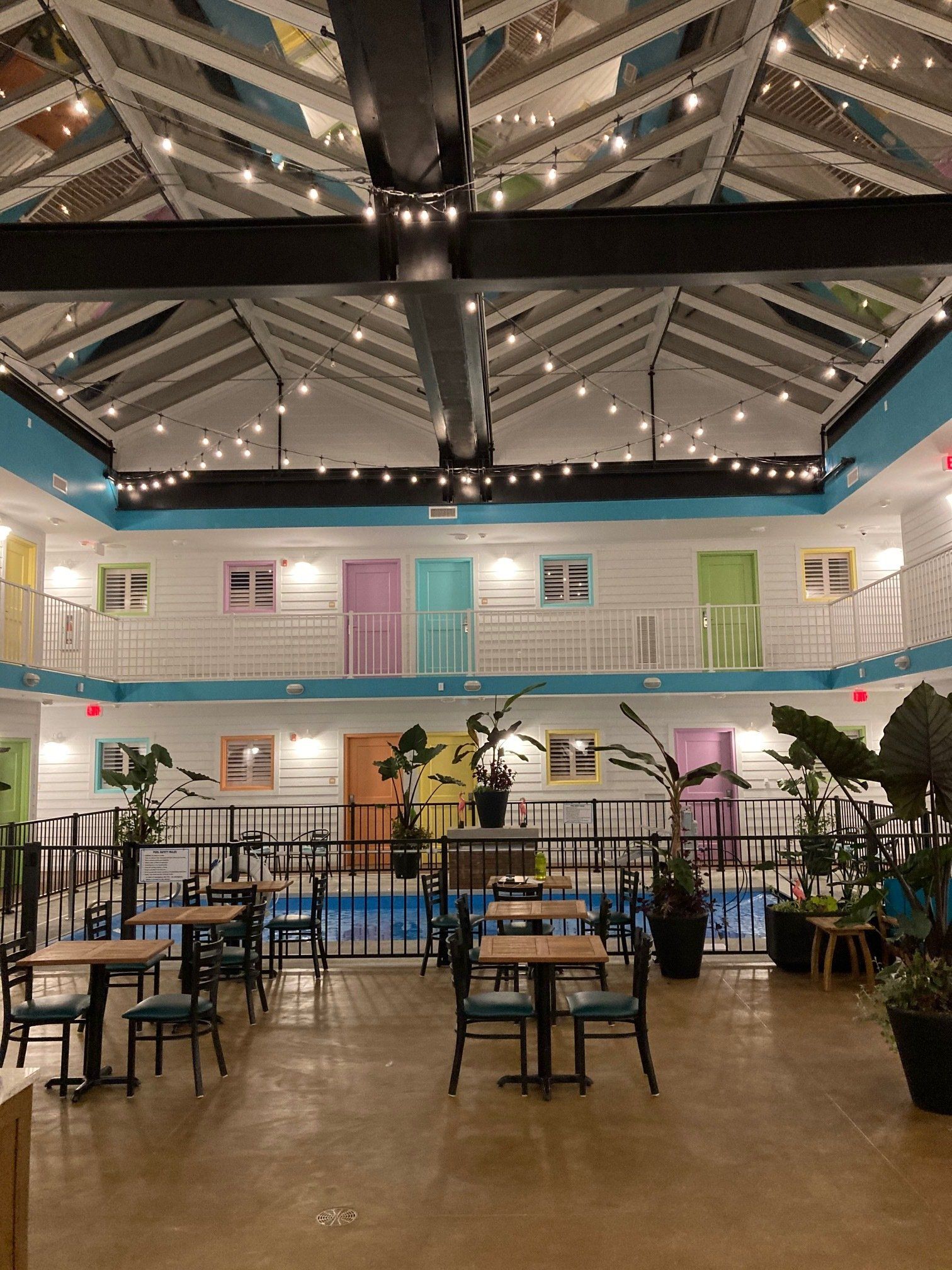 A large room with tables and chairs and a pool in the middle.