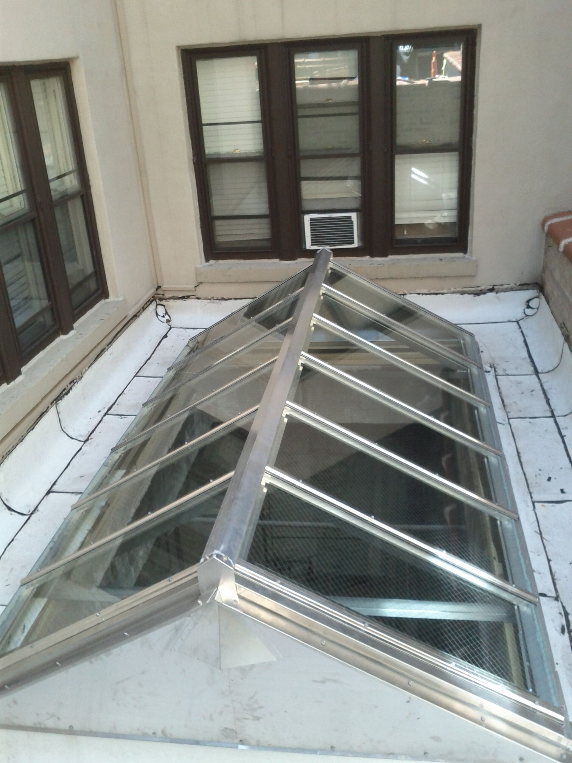 A skylight on the roof of a building with a window in the background.