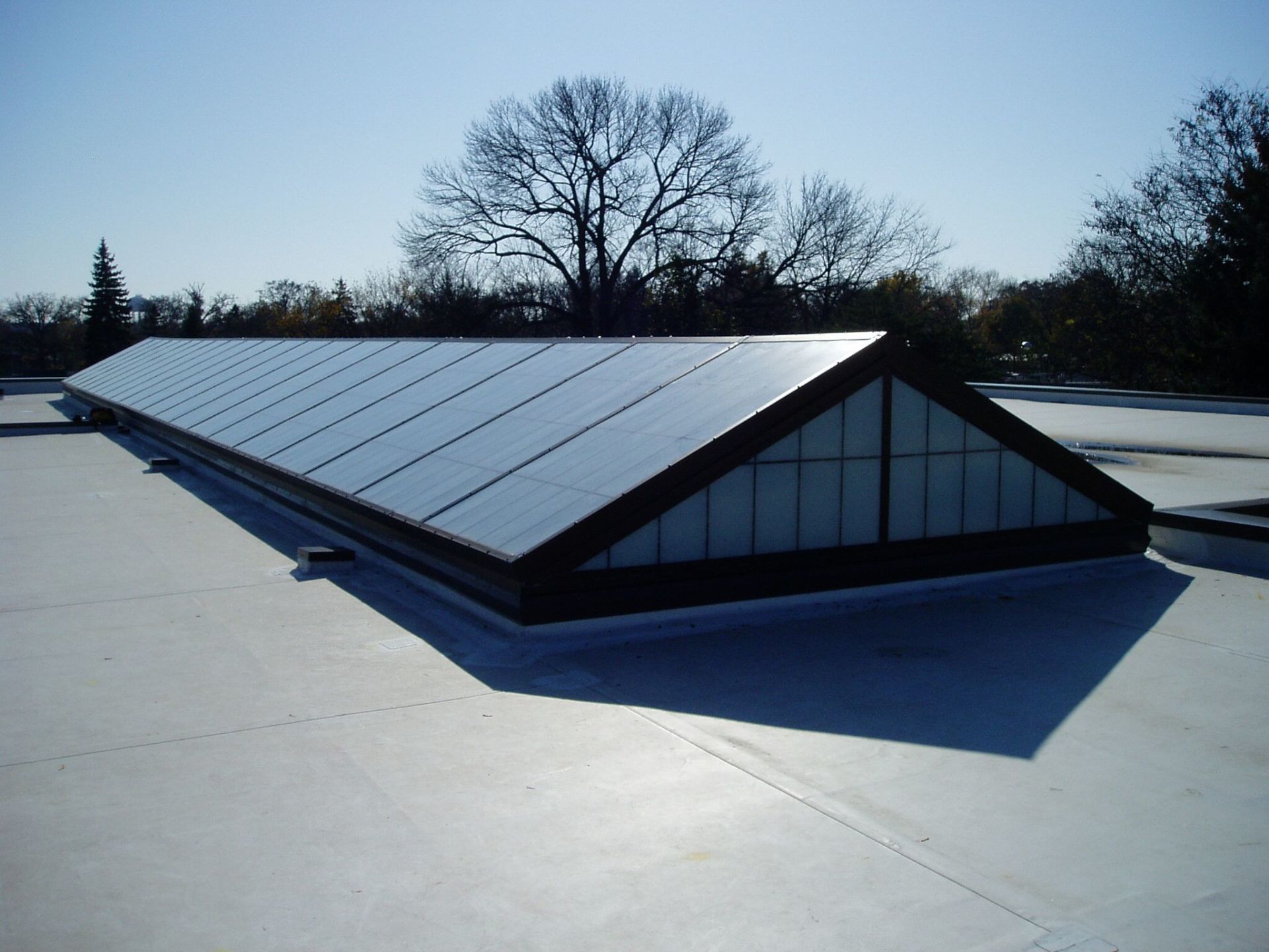 A roof with a triangle shaped window on it