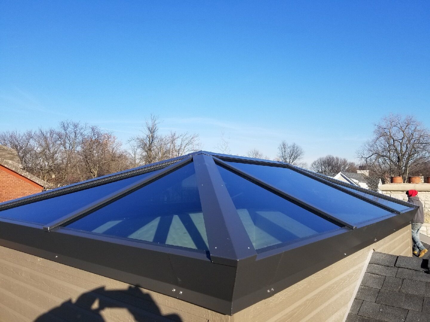A person is taking a picture of a skylight on the roof of a building.