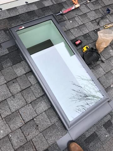 A skylight is sitting on top of a brick roof.