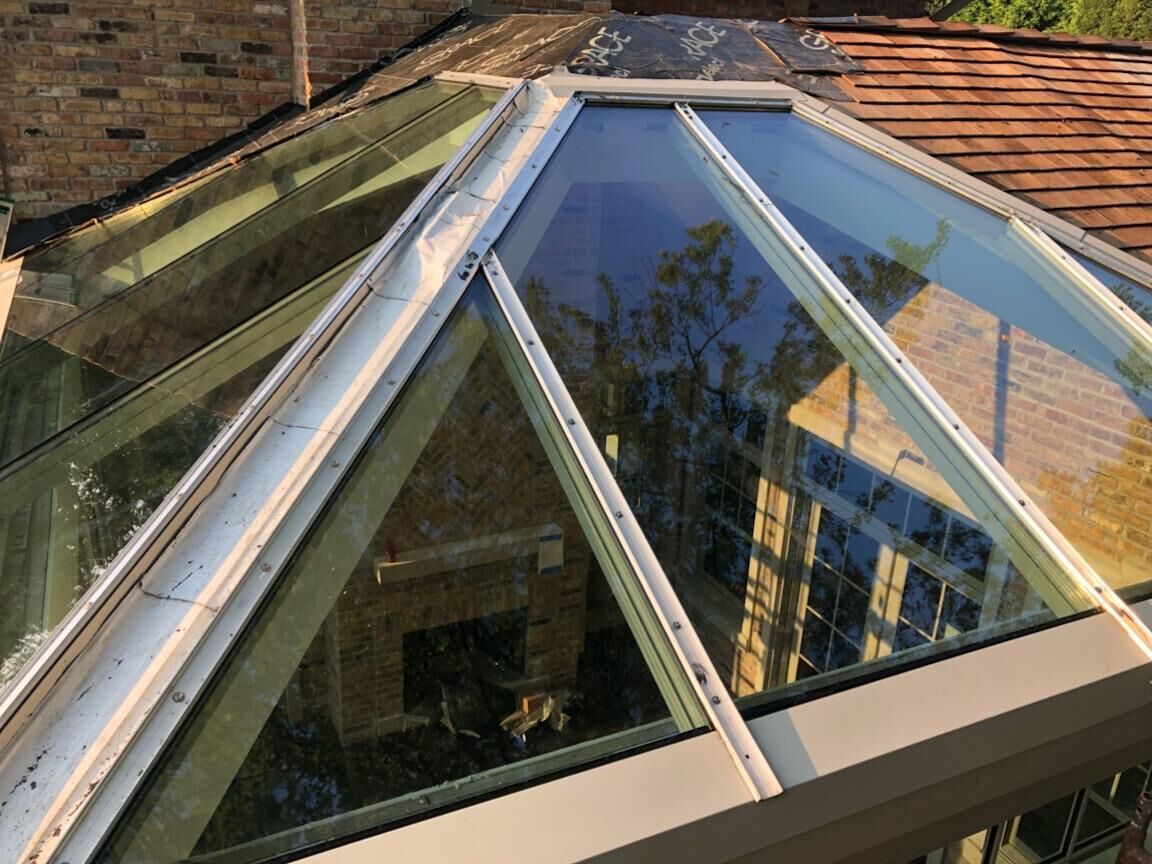 A large glass roof with a brick building in the background.