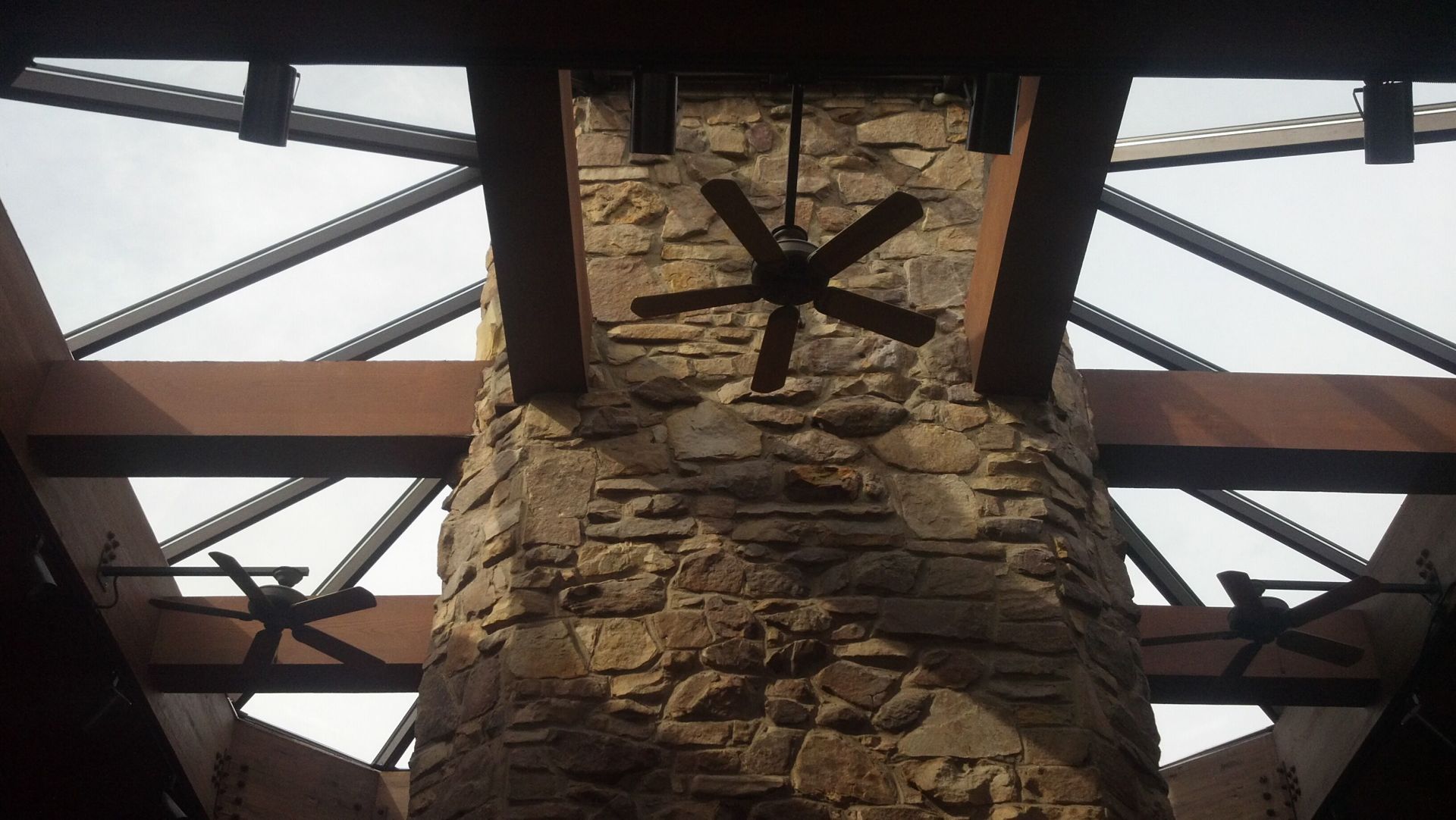 A stone chimney with a ceiling fan hanging from it