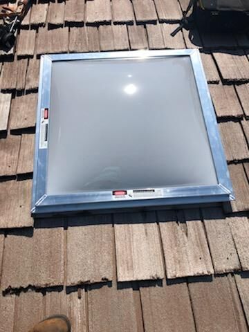 A skylight is sitting on top of a wooden roof.