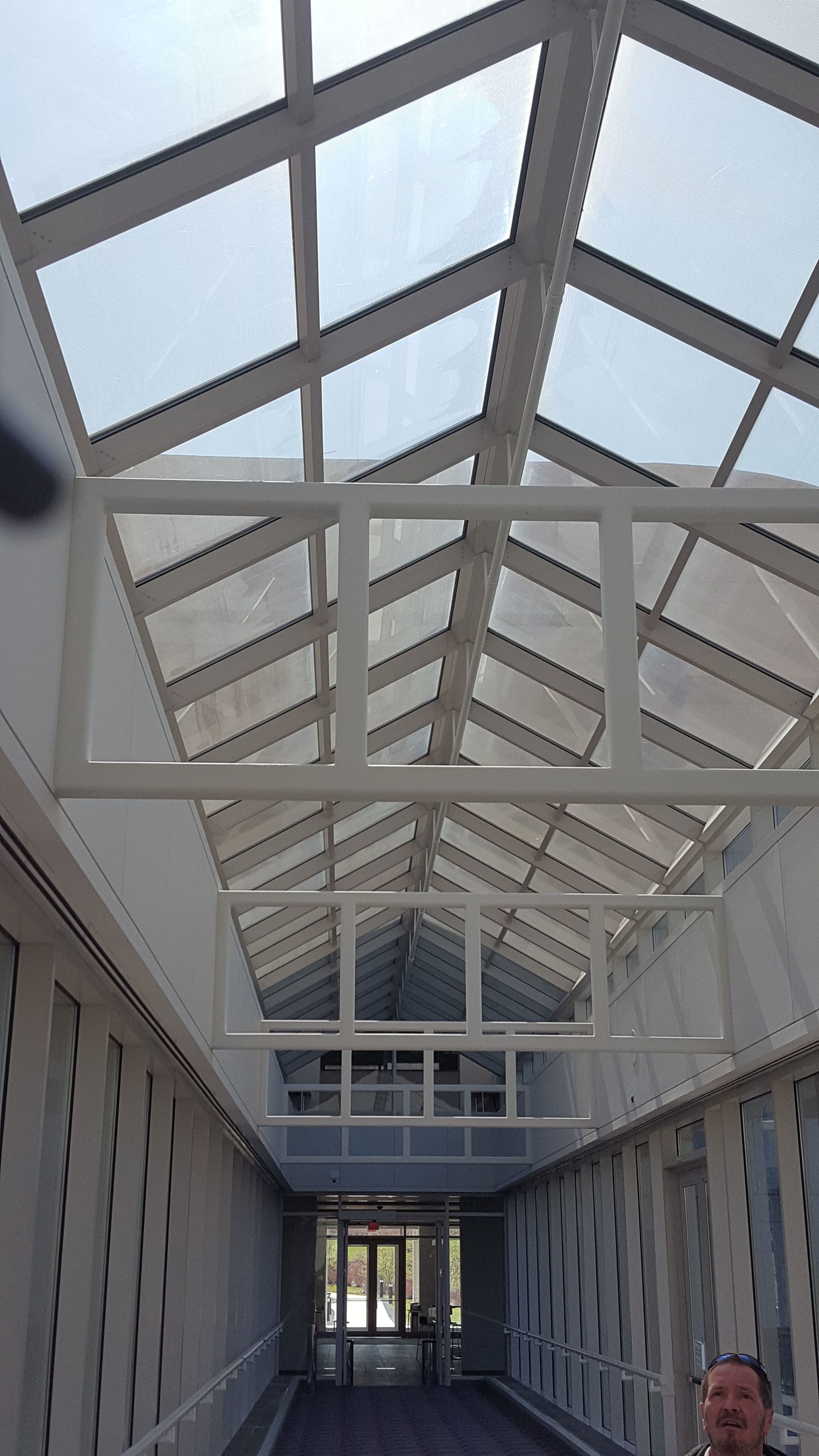 A man is standing in a hallway with a glass roof.