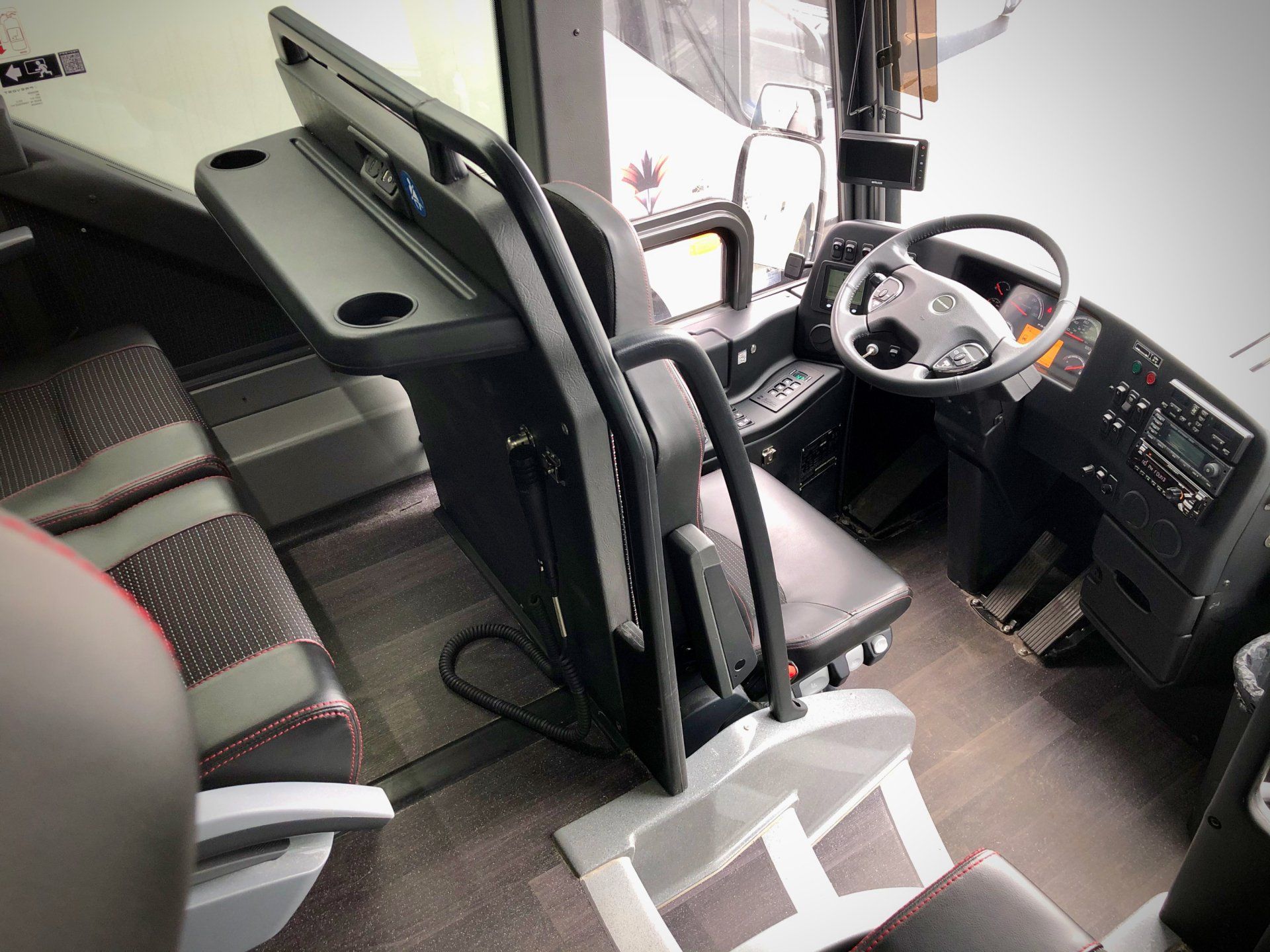 The inside of a bus with a steering wheel and a table.