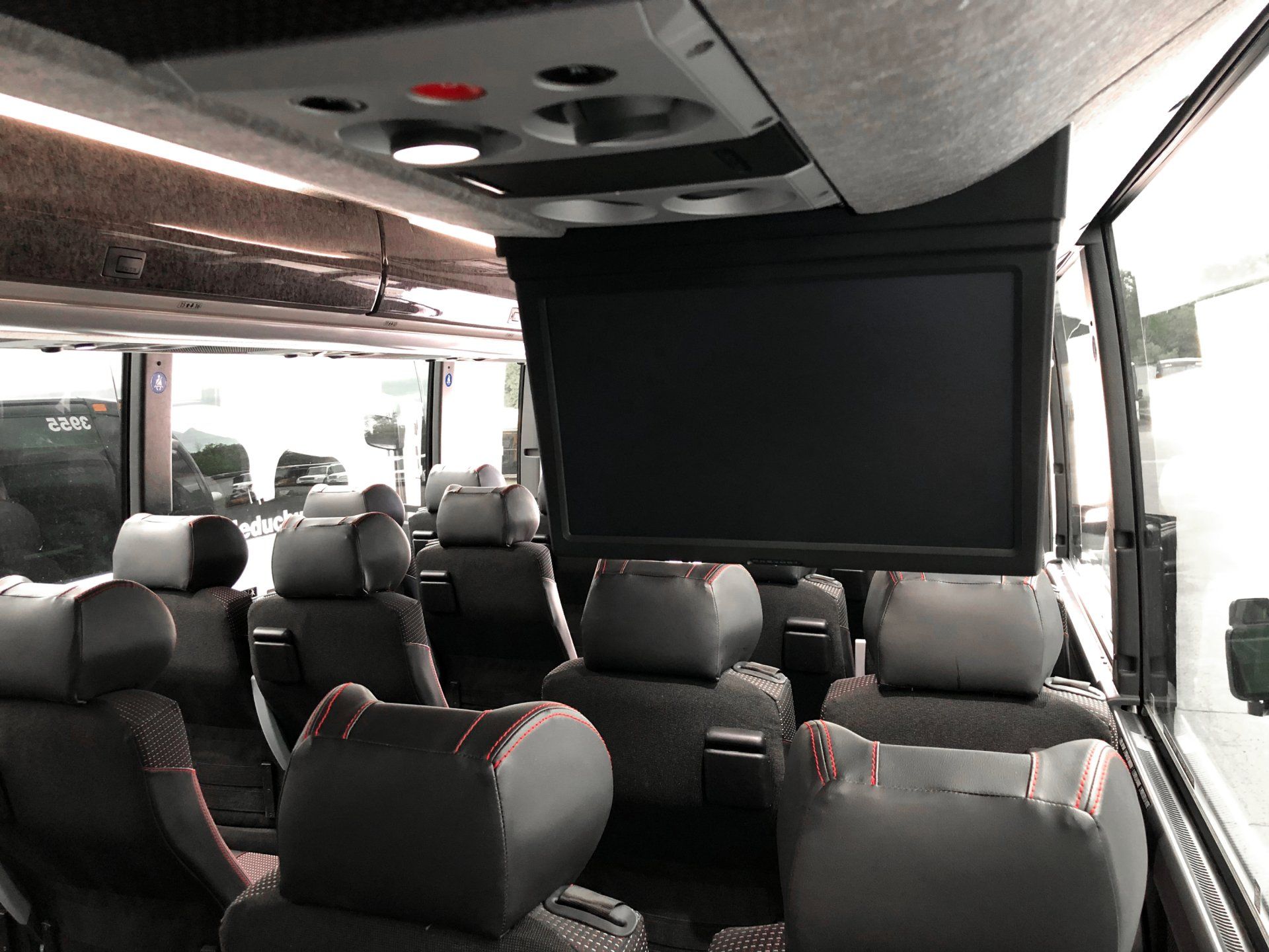 The inside of a bus with a tv mounted to the ceiling