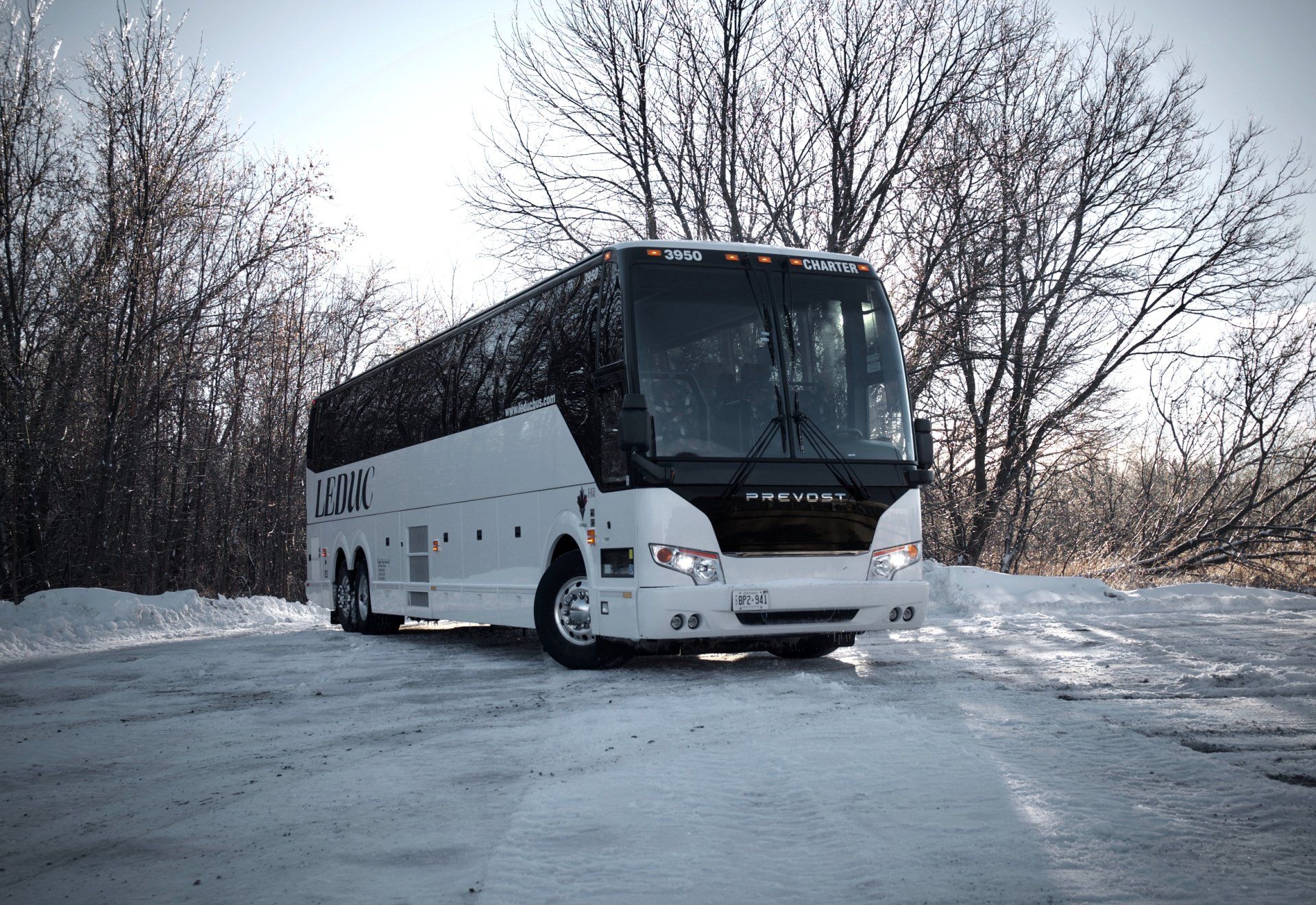 A white bus is parked in a snowy parking lot