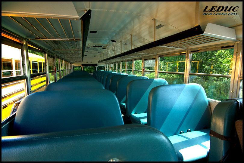 The inside of an empty school bus with blue seats
