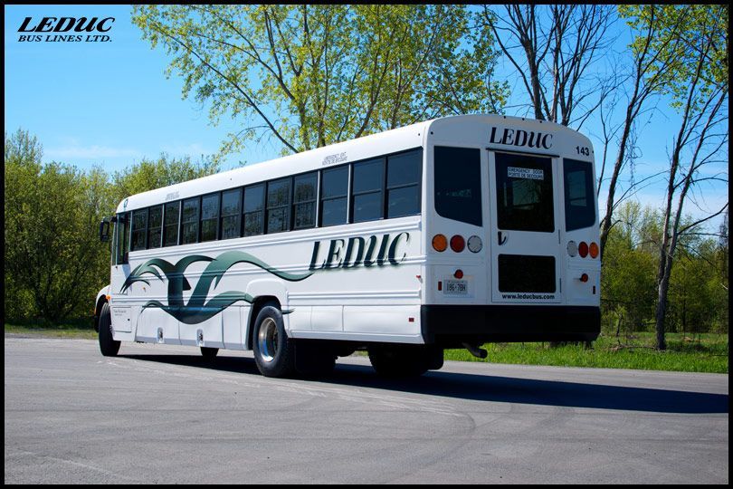 A white leduc bus is parked on the side of the road