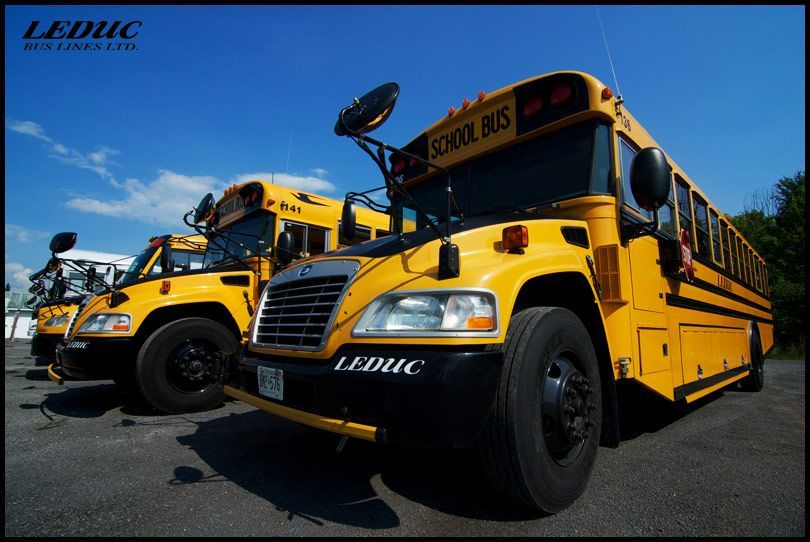 Two yellow school buses are parked next to each other