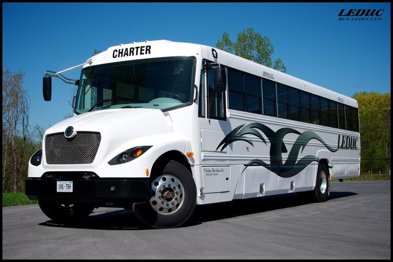 A white charter bus is parked in a parking lot