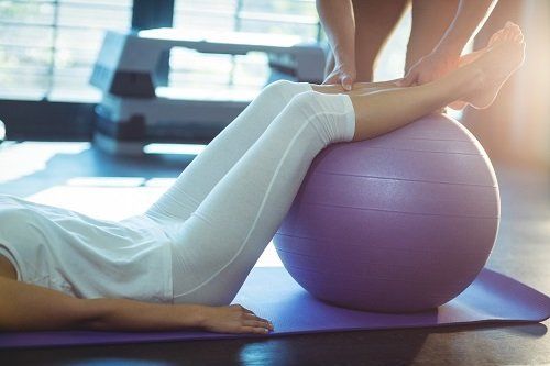 Terapeuta collocando le gambe della paziente sulla palla di pilates