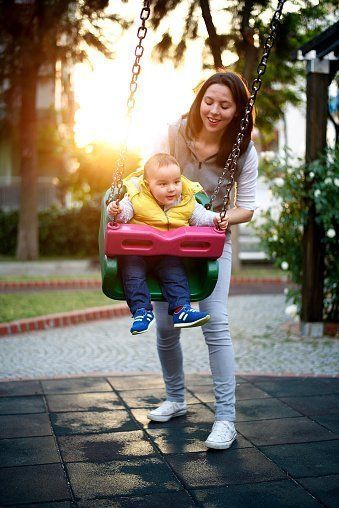 una donna mentre gioca con bambino su appesa amaca in un giardino