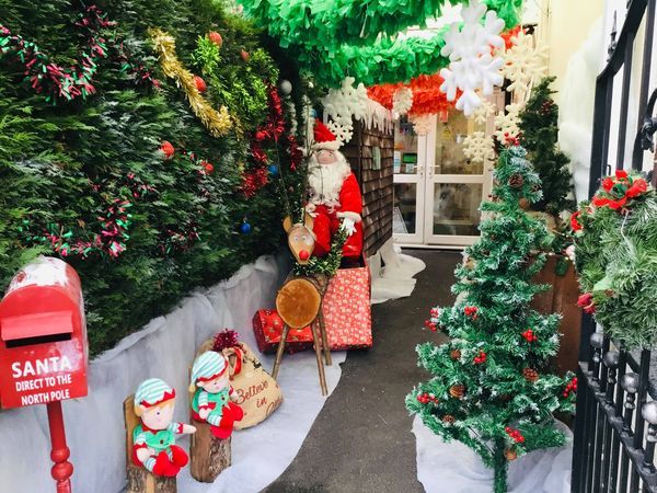 Decorated Christmas walkway with wreaths, Santa figures, and festive red-and-green decorations