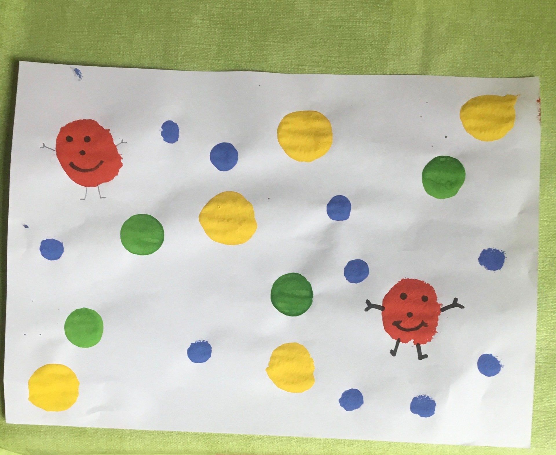 Hand-drawn red and yellow smiley faces with colorful dots on white paper.