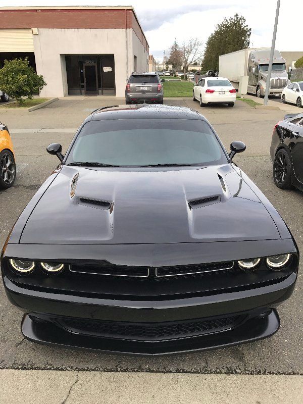 A black dodge challenger is parked in front of a building.