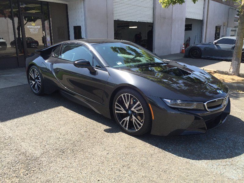 A black bmw i8 is parked in front of a building.