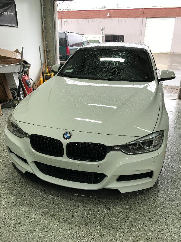 A white bmw is parked in a garage.