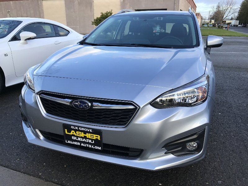 A silver subaru is parked next to a white car.