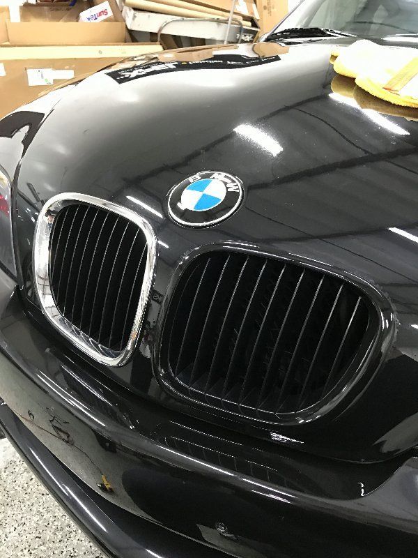A black bmw with a blue and white bmw logo on the hood