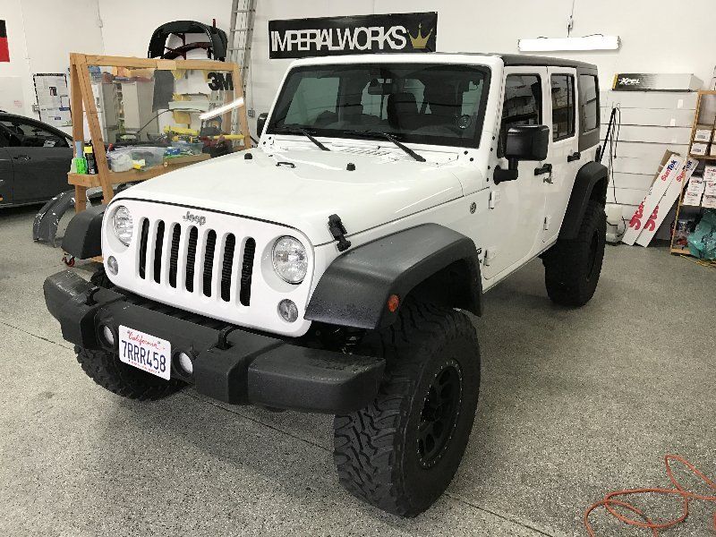 A white jeep is parked in a garage.