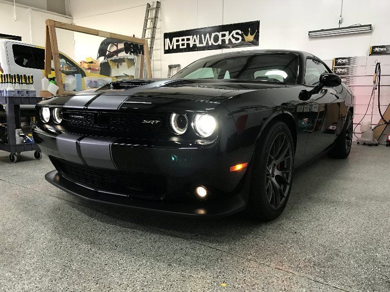 A black dodge challenger is parked in a garage.
