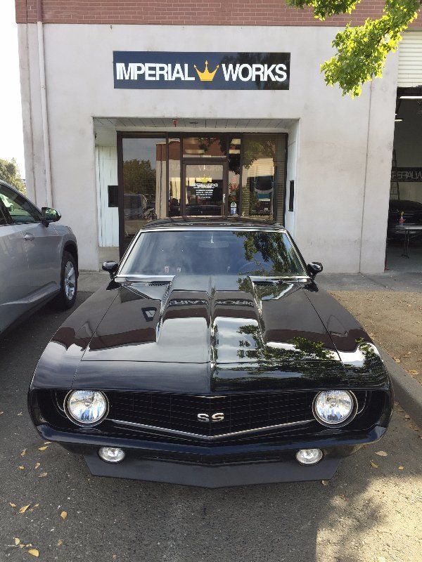 A black car is parked in front of a building that says imperial works