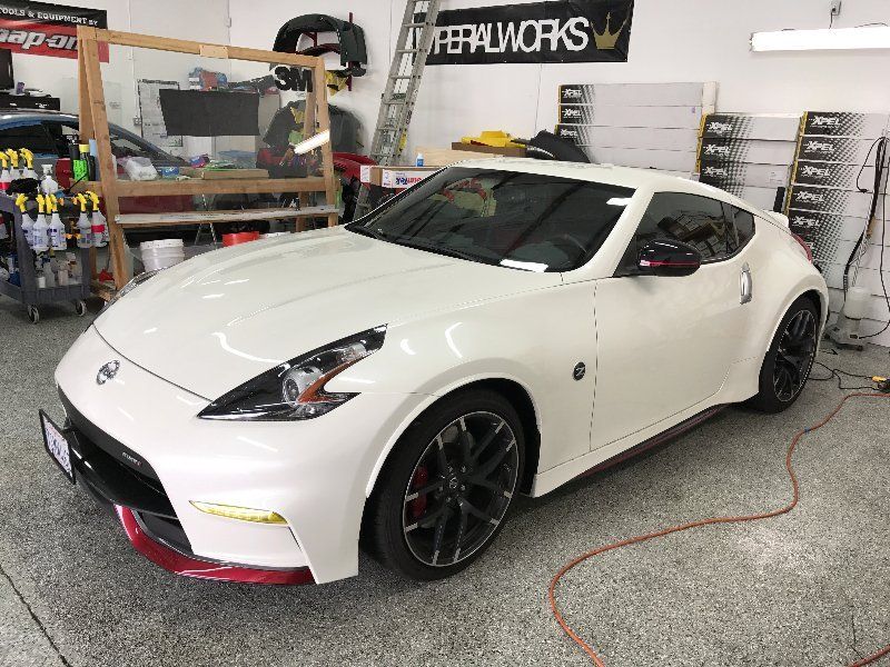 A white nissan 370z is parked in a garage.
