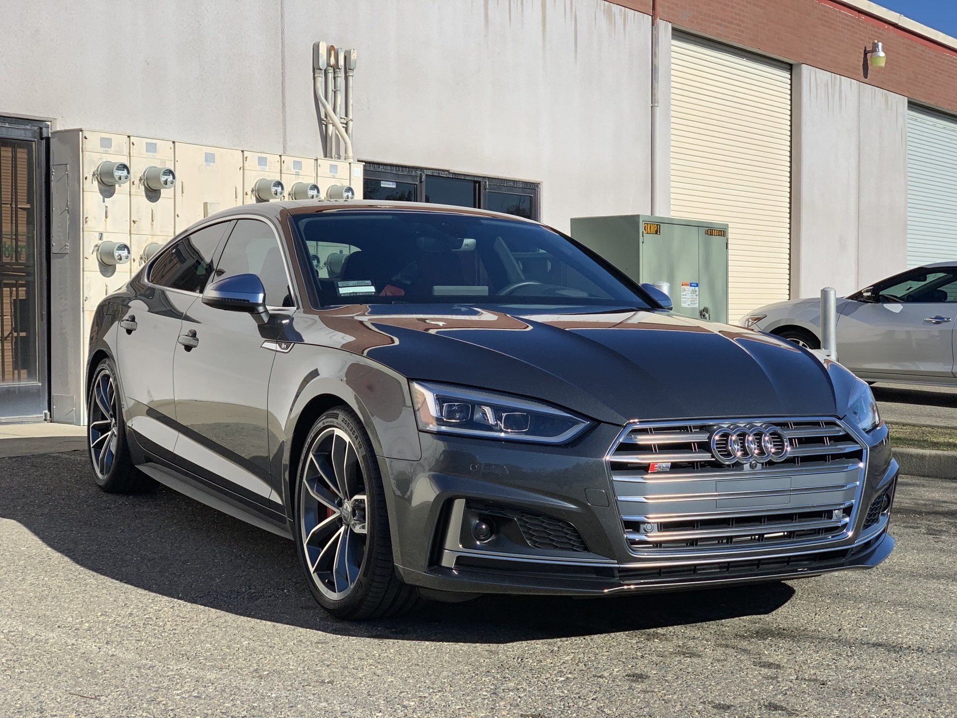 A gray audi a5 is parked in front of a building.