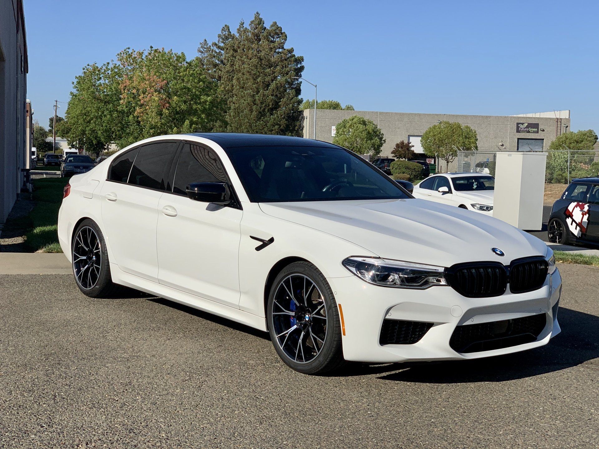 A white bmw m5 is parked in front of a building.