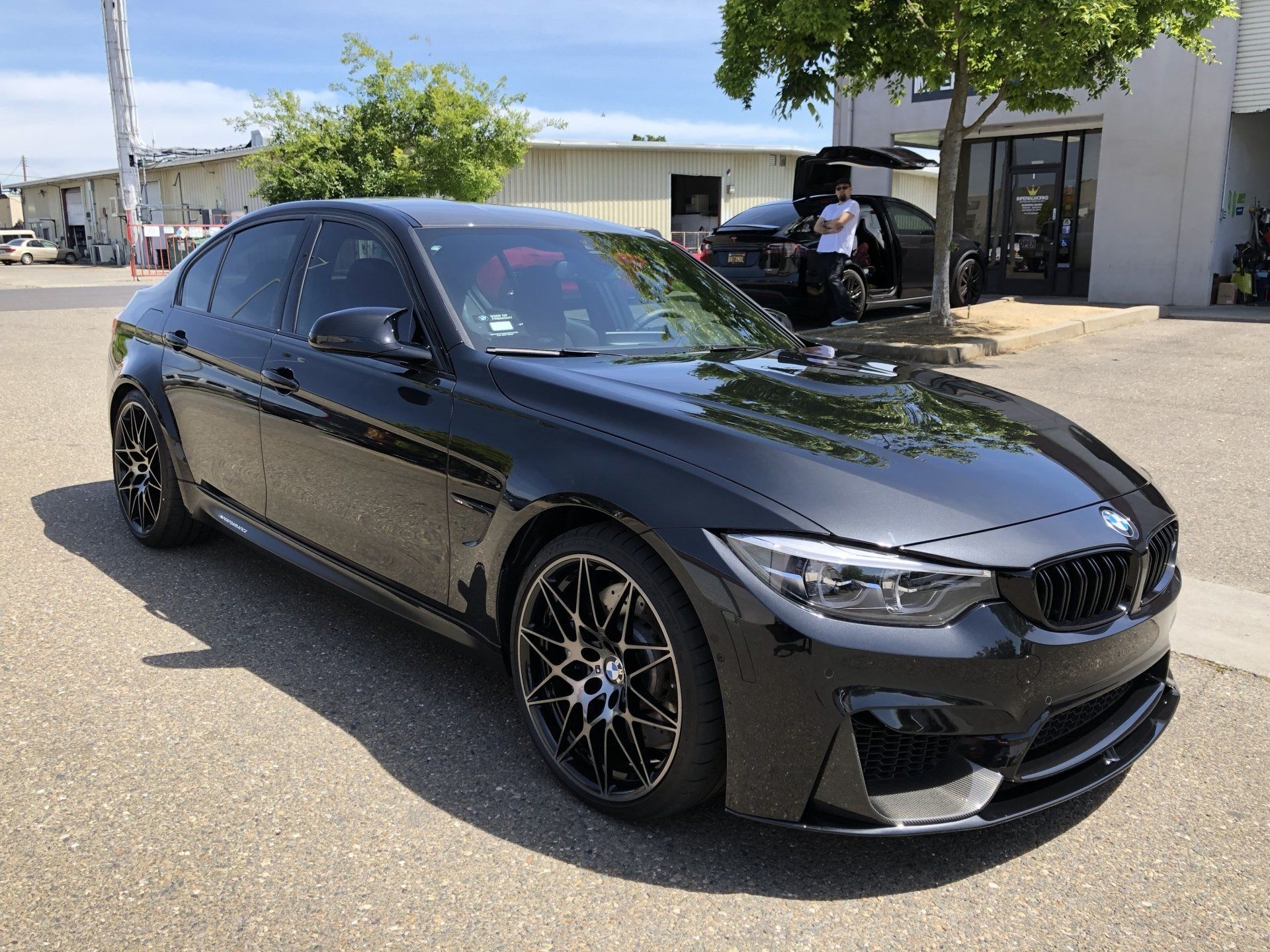A black bmw m3 is parked in front of a building.
