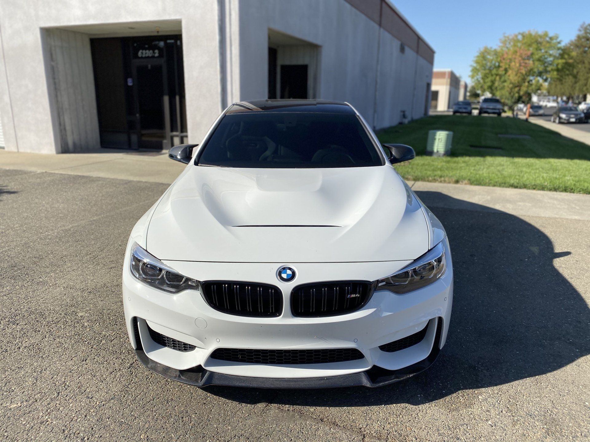 A white bmw m3 is parked in front of a building