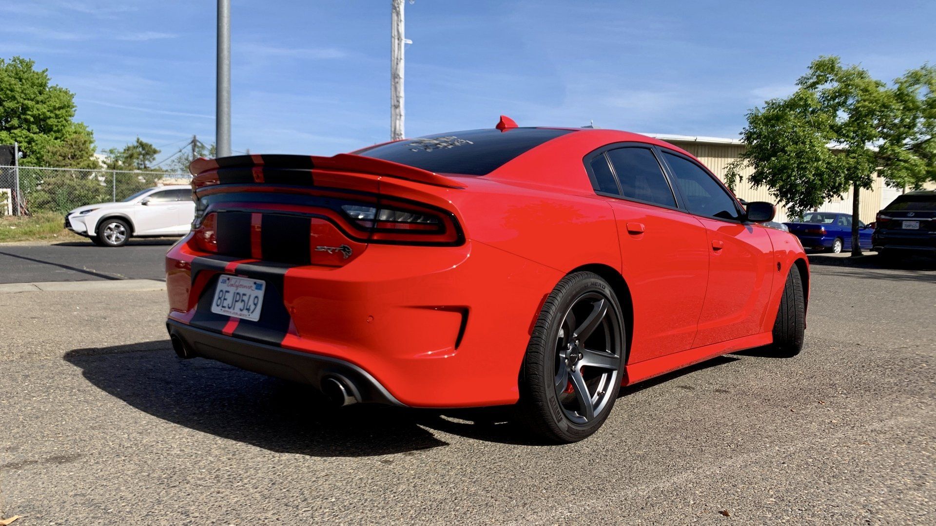 A red dodge charger is parked in a parking lot.