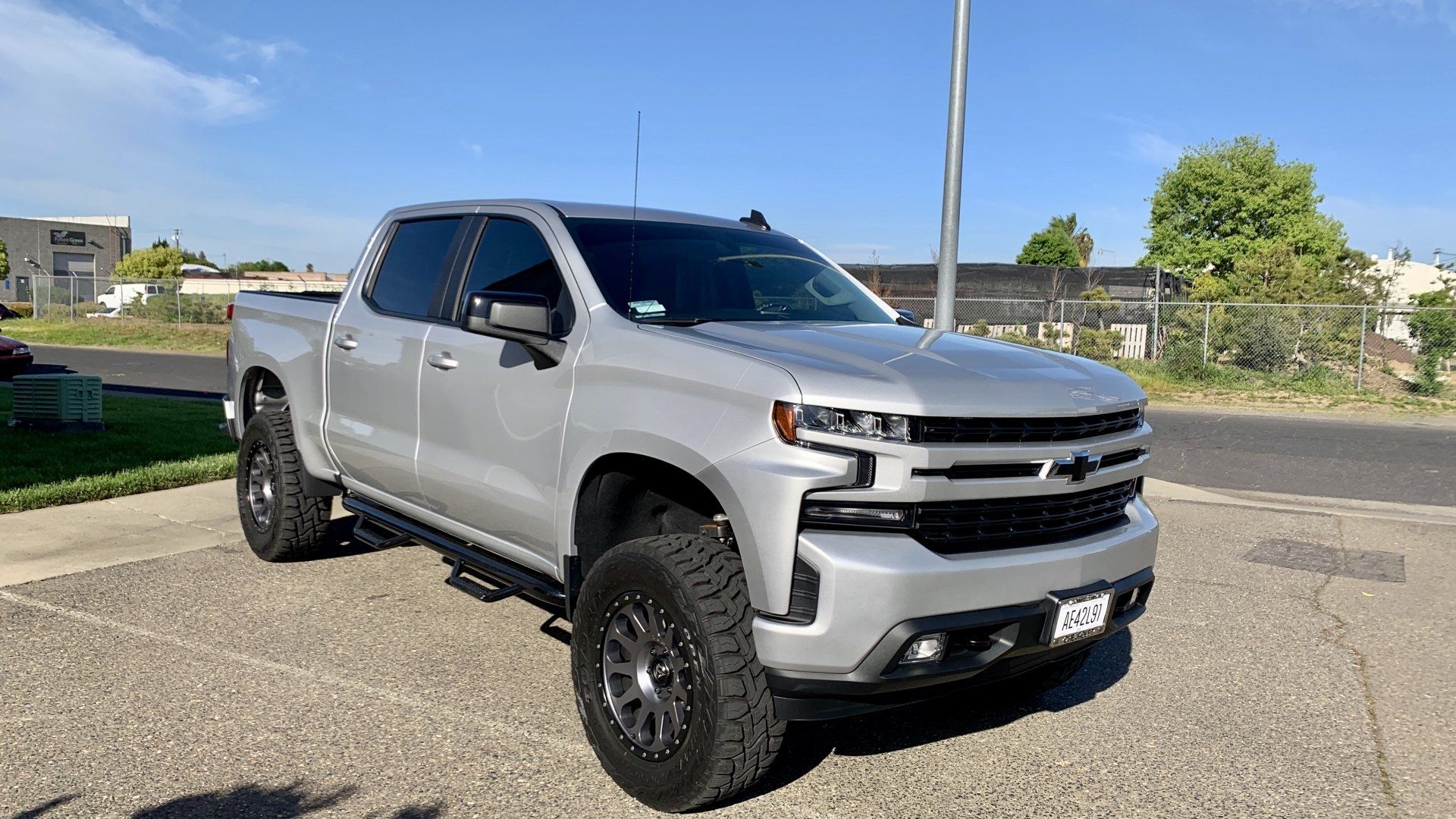 A silver truck is parked on the side of the road.