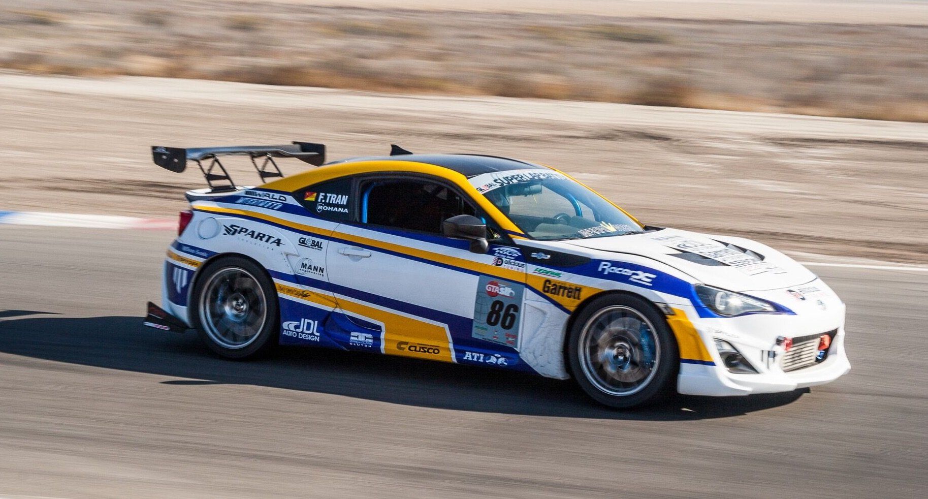 A white and yellow race car is driving down a track.