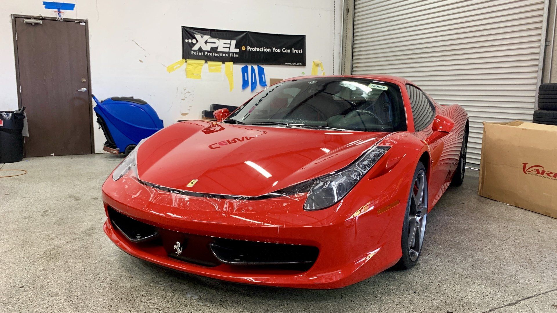 A red sports car is parked in a garage with paint protection and clear bra