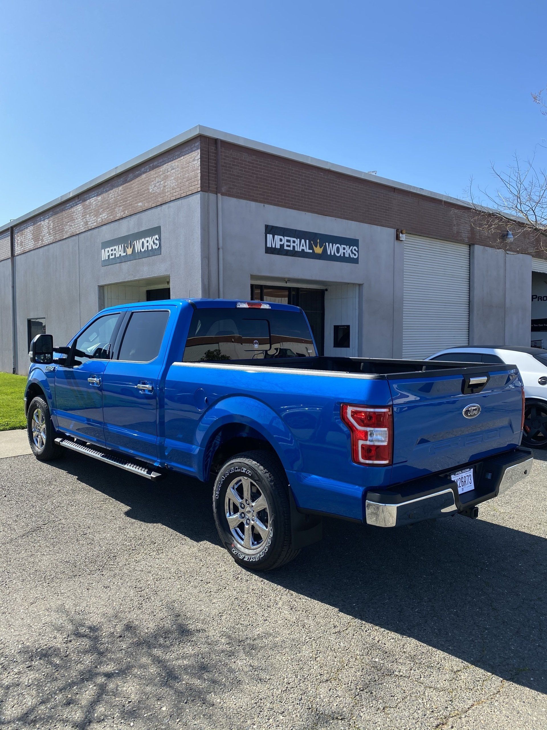 A blue pickup truck is parked in front of a building.