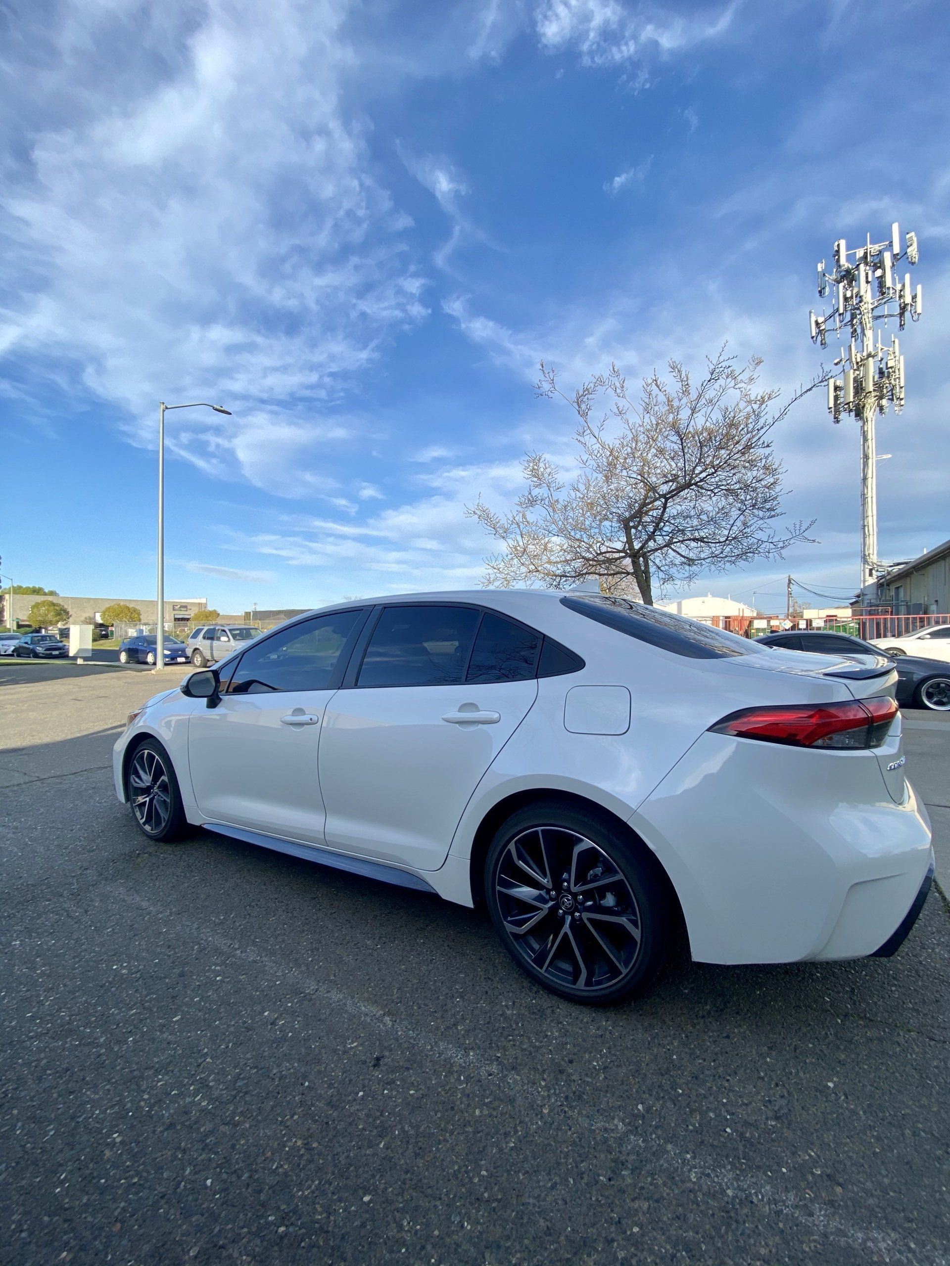 A white toyota corolla is parked in a parking lot.