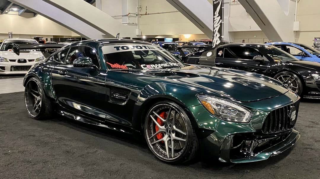 A green mercedes amg gt is parked in a showroom.