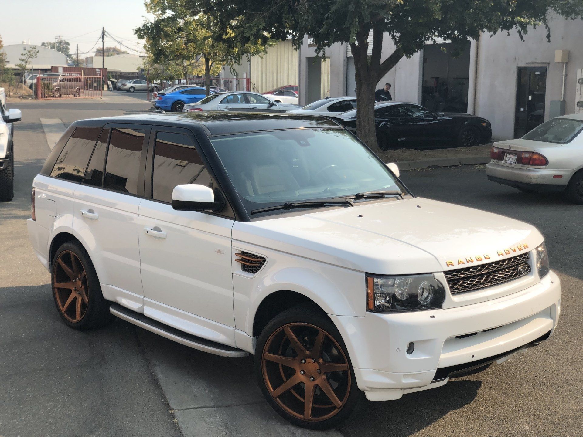 A white range rover sport is parked on the side of the road.