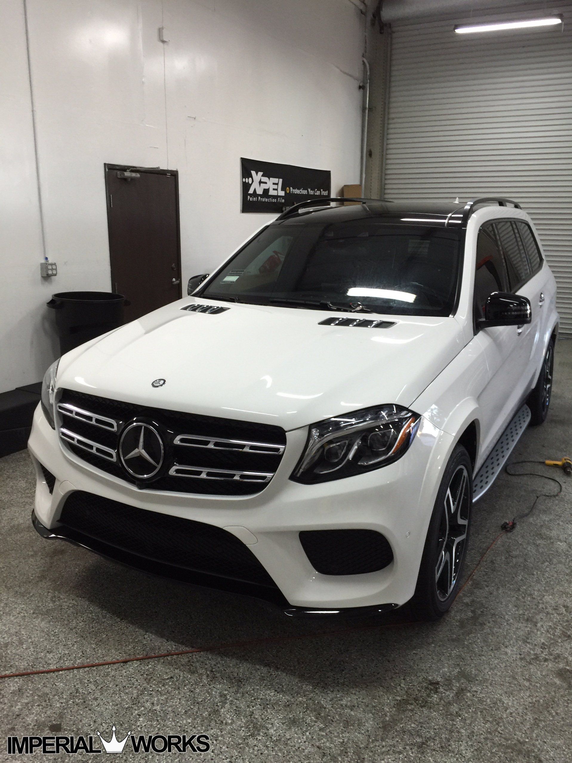 A white mercedes benz suv is parked in a garage.