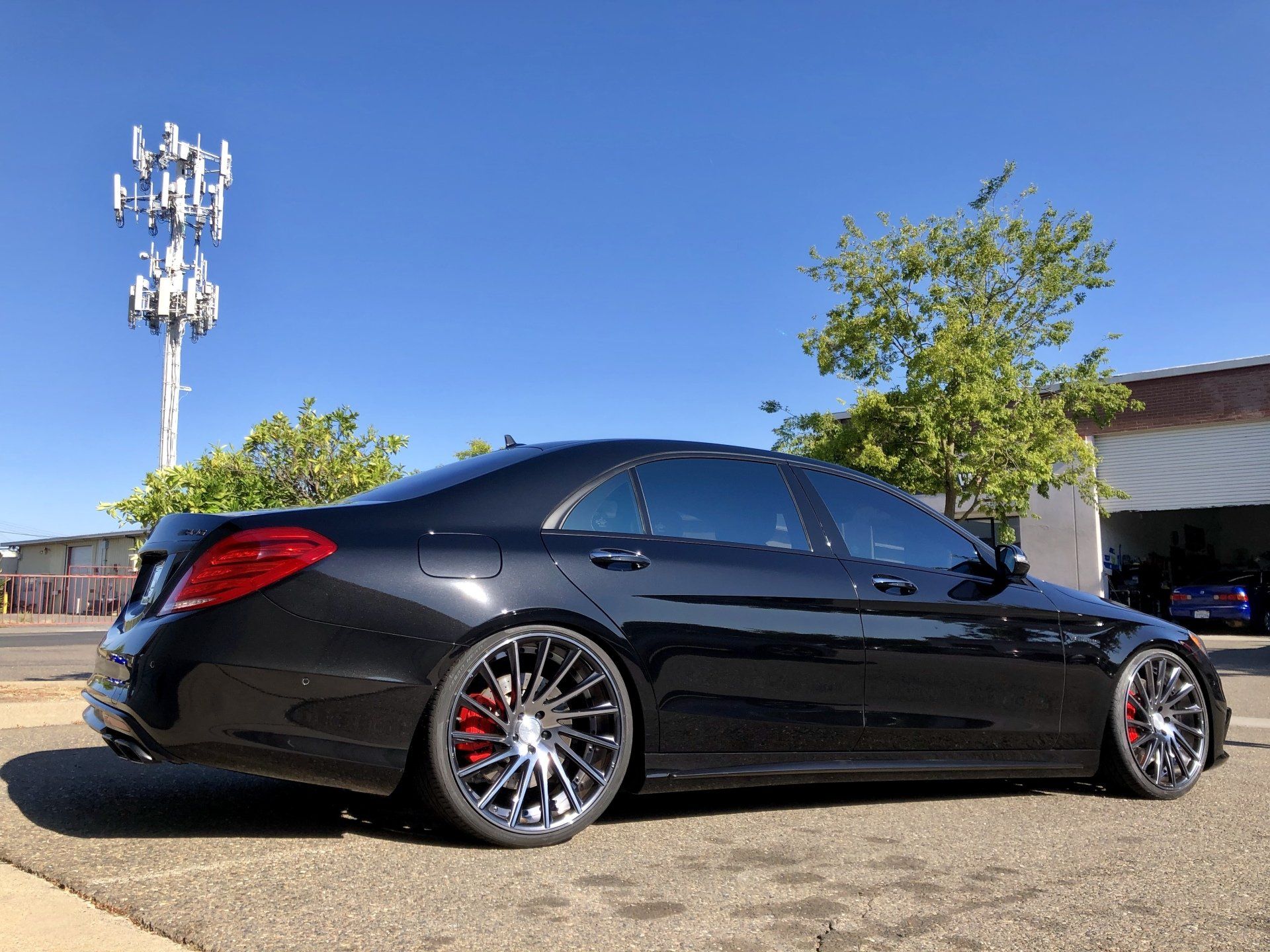 A black mercedes benz s63 amg is parked in front of a garage.