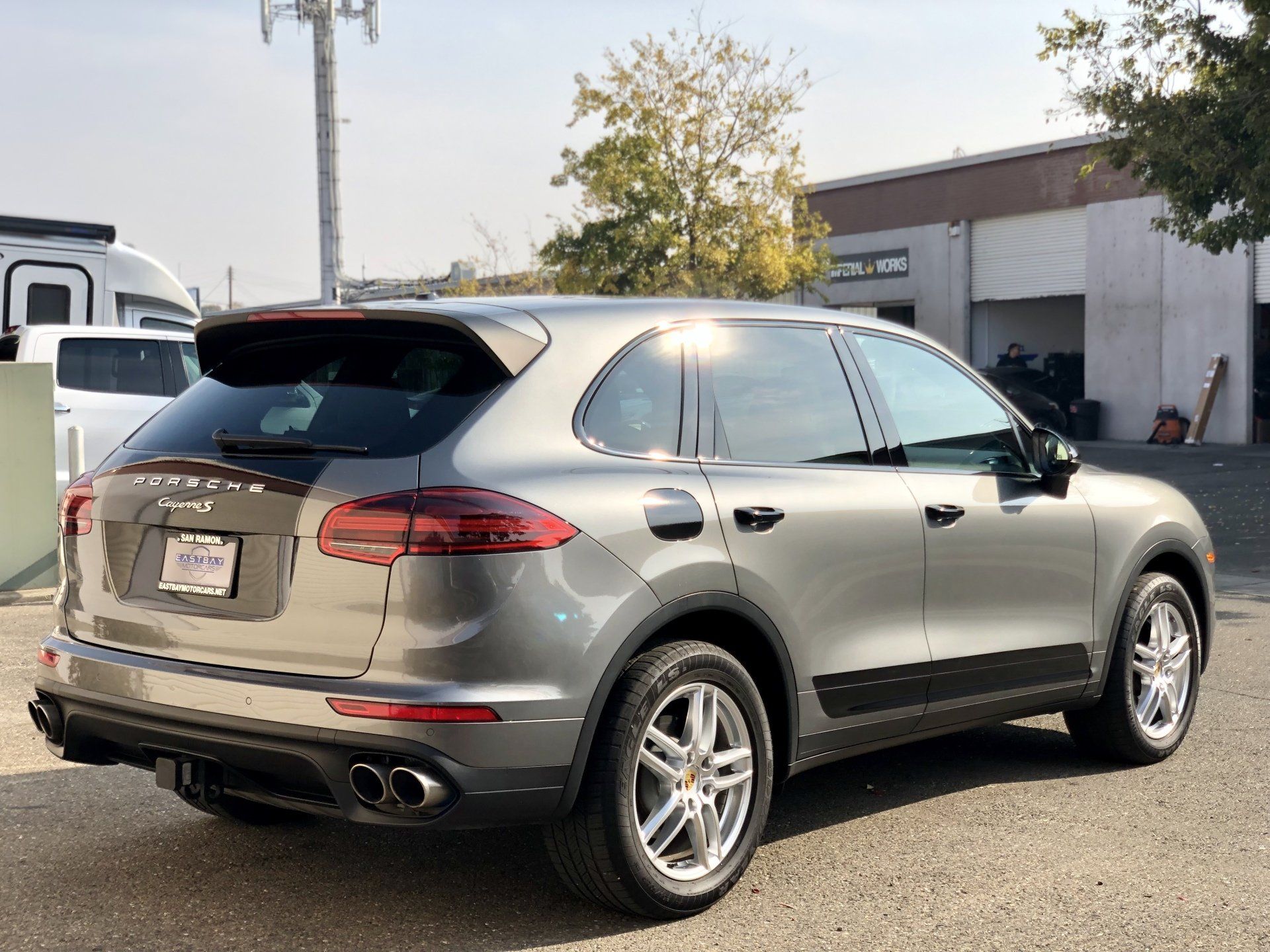 A silver porsche cayenne is parked in front of a building.