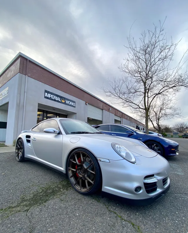 Two silver sports cars are parked in front of a building.