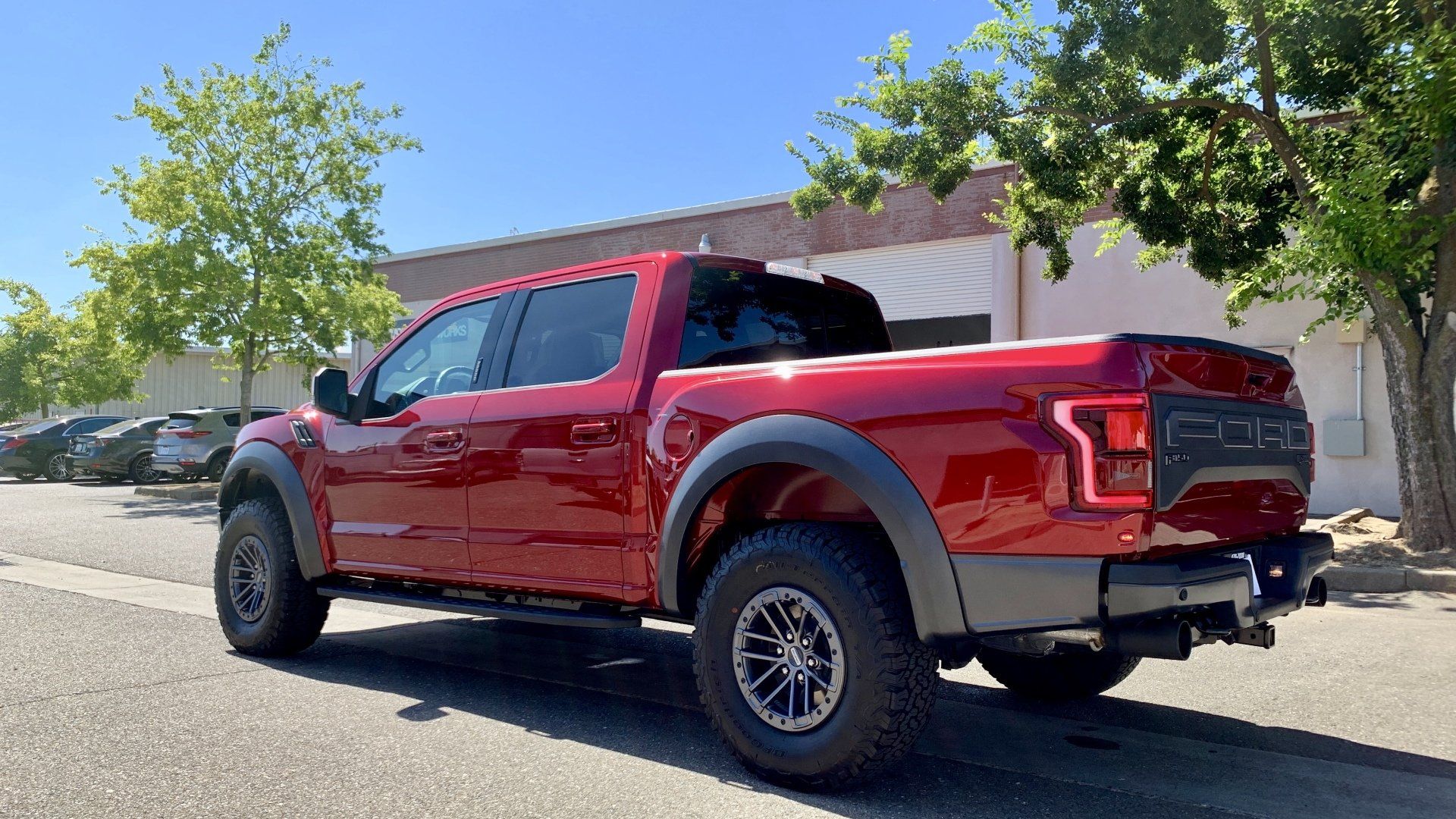 A red pickup truck is parked on the side of the road in front of a building.