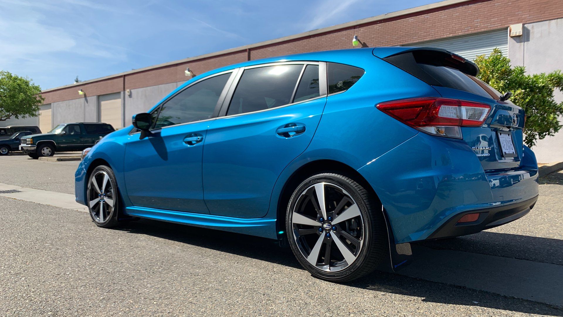 A blue subaru impreza is parked in front of a building.